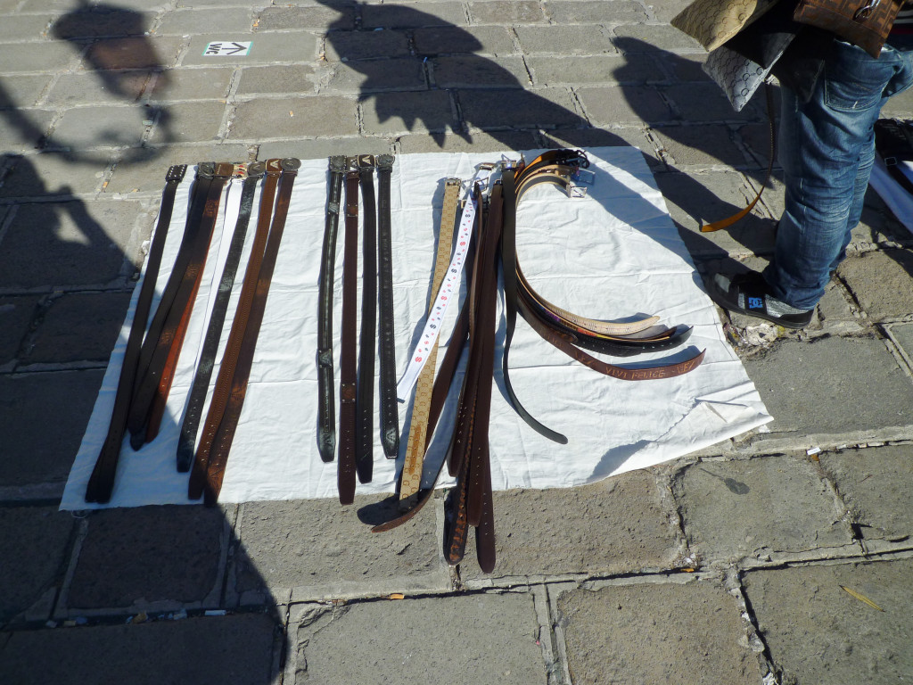 Several belts are spread out on a white cloth.