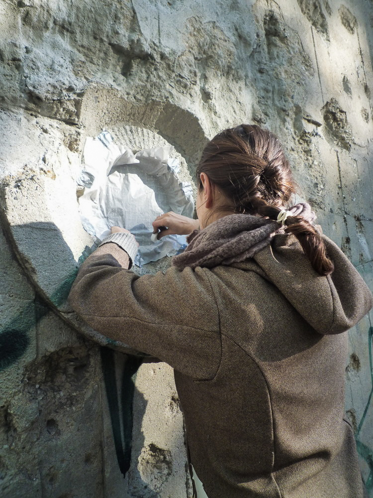 Nadia Kaabi-Linke taking transfer prints rom a damaged wall.
