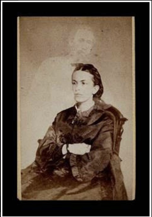 Archival photograph of a woman on a chair and a ghost-like appearance behind her.