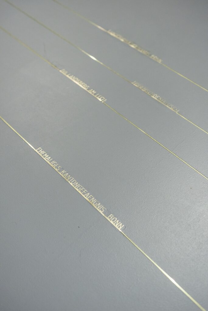 Outlines of prison cells inlayed in a grey platforlm as an art installation