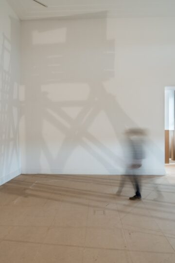 Painted shadow of a watchtower, stretching over the floor and up the corner of the wall, All along the Watchtower, 2012, Nadia Kaabi-Linke