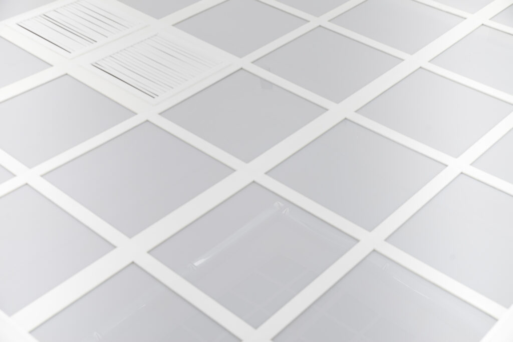 Milky acrylic glass divided into equal-sized squares. Two of these squares are reminiscent of the openings of air shafts.