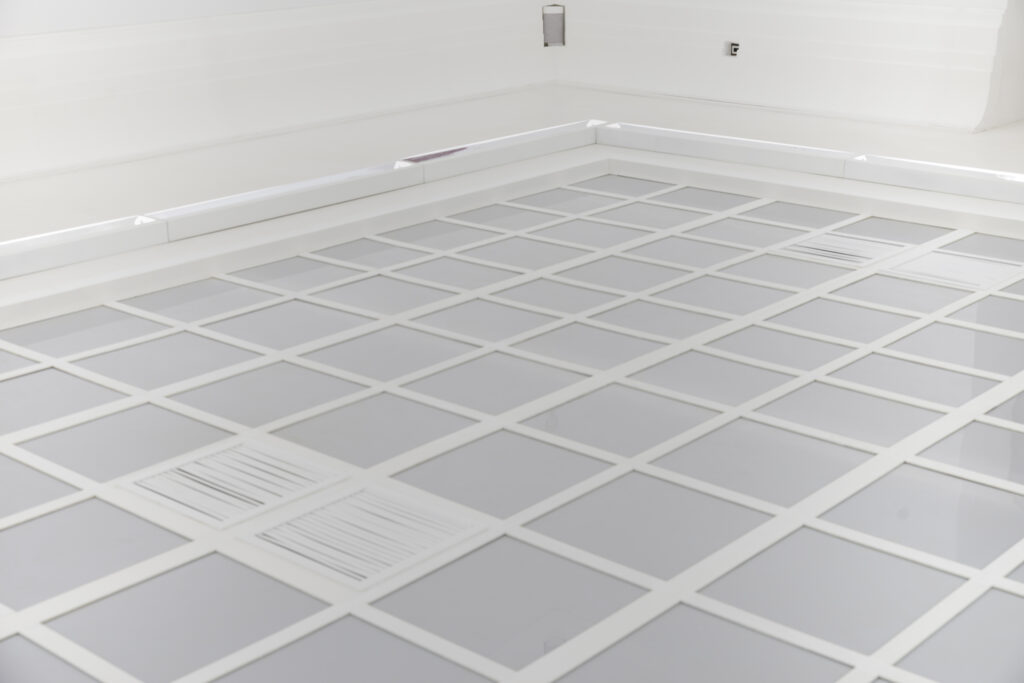Milky acrylic glass divided into equal-sized squares. Two of these squares are reminiscent of the openings of air shafts.