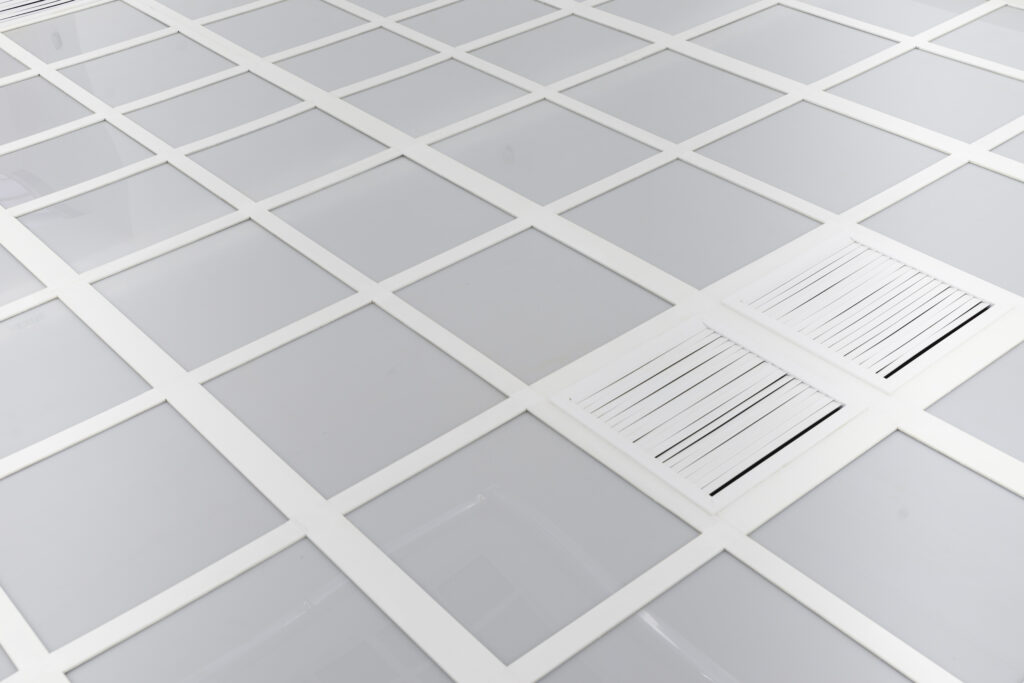 Milky acrylic glass divided into equal-sized squares. Two of these squares are reminiscent of the openings of air shafts.