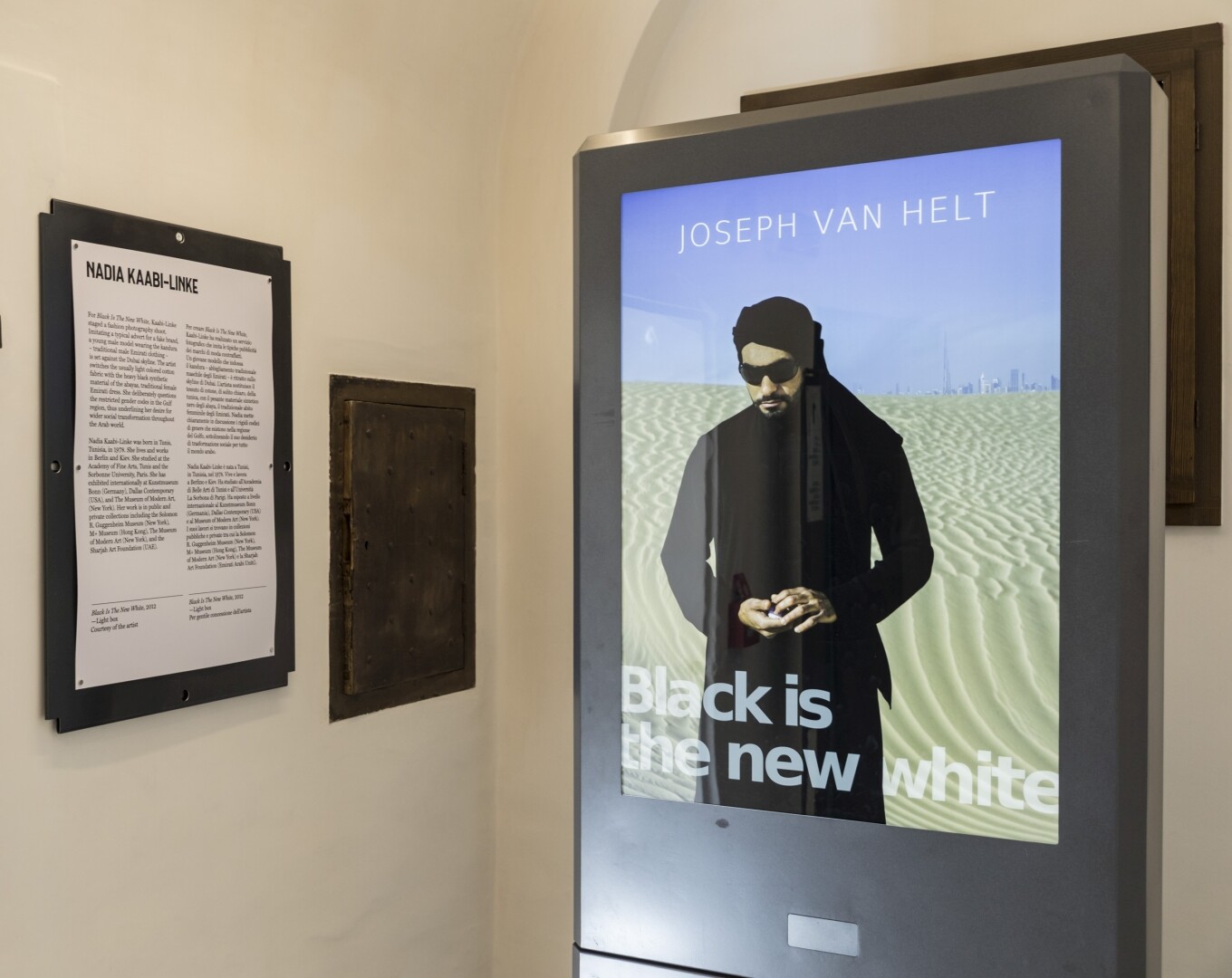 On a screen a photo of a man in the desert, next to it an information board
