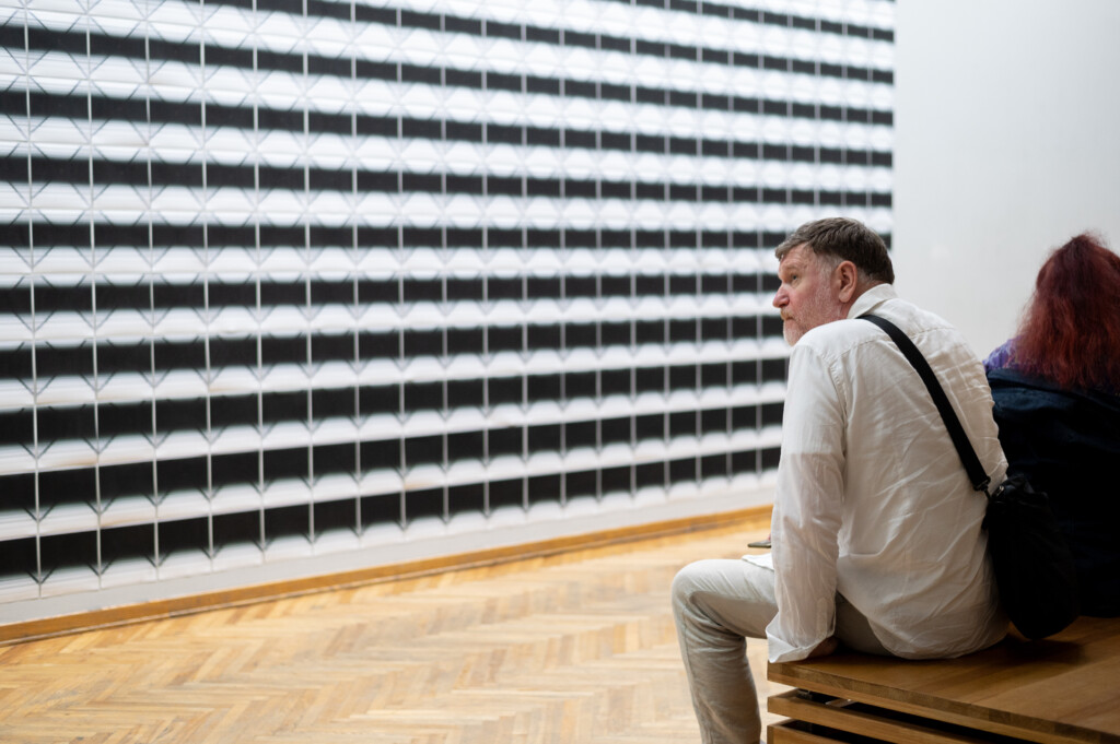 A man looking at an artwork, covering the wall in front of him.