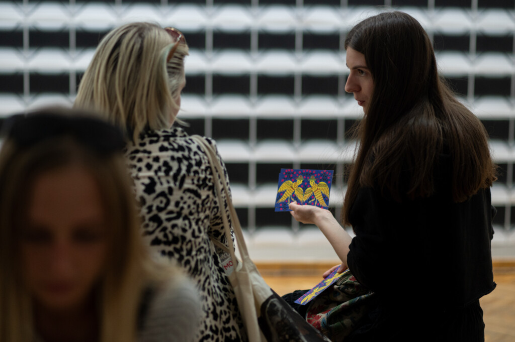 Visitors in an exhibition space talking to each other.