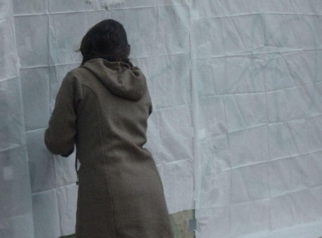 In the making off, Off the Wall, 2008, a weathered Berlin façade with bullet-marked ornaments, symbolizing war's remnants and resilience amid change, transferred onto canvas by the artist Nadia Kaabi-Linke