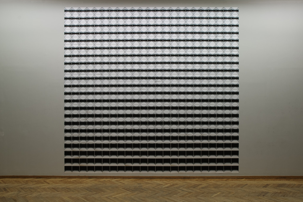 An artwork made of many pictures aligned in a big square, creating a black and white pattern, hanging on the wall of an exhibition space / SqueeSqueezed in Infinity II (Installation view), NAMU_Kyiv, 2023 Nadia Kaabi-Linkezed in Infinity II (Detail view), NAMU_Kyiv, 2023 Nadia Kaabi-Linke