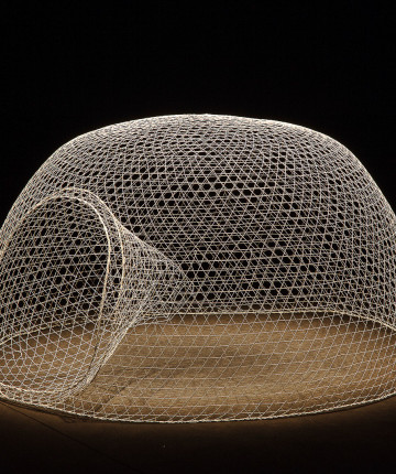 A dome-shaped wire mesh sculpture placed under a spotlight in an otherwise dark room. Nadia Kaabi-Linke Smooth Criminal