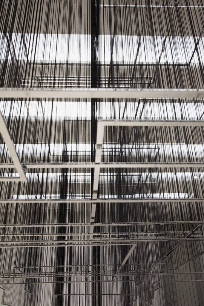 Abstract image of polished steel frames hanging on black threads with shadows on the wall. At Guggenheim Museum, New York.