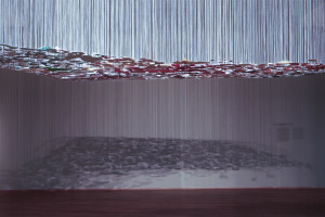 Colored wall pieces with paint hanging on white threads are casting shadows on the museum's wall.