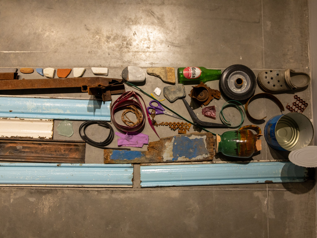 A line of different, weathered, objects laying on a concrete floor.