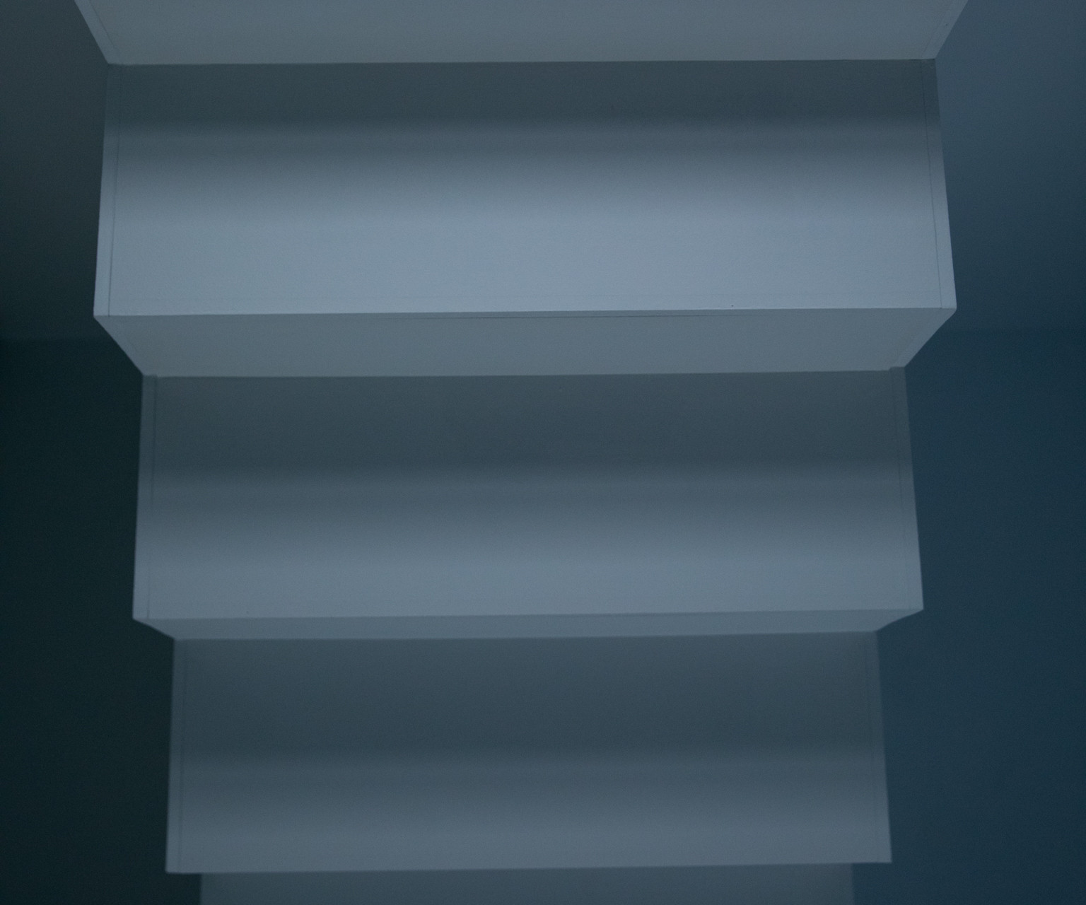 Part of a white staircase illuminated from the top part.