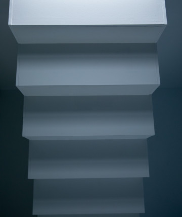 Part of a white staircase illuminated from the top part.