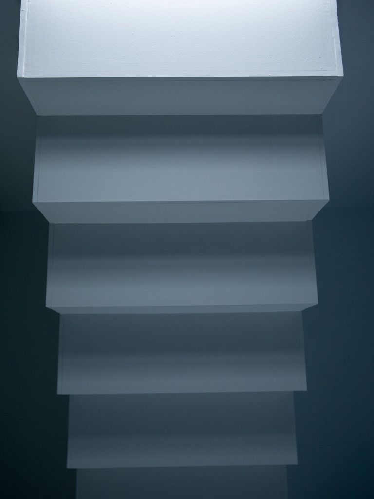 Part of a white staircase illuminated from the top part.