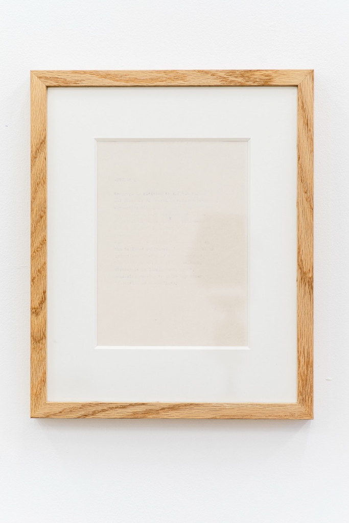 Paperwork with faded text in a wooden frame.