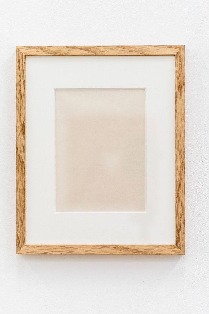 Paperwork with faded text in a wooden frame.