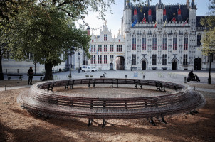 In a public space, benches are placed to create a circle. The benches are covered in bird spices.
