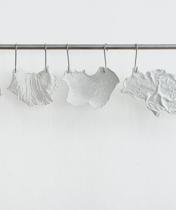 Fragile plaster casts hang like meat at the butcher's on a white wall.