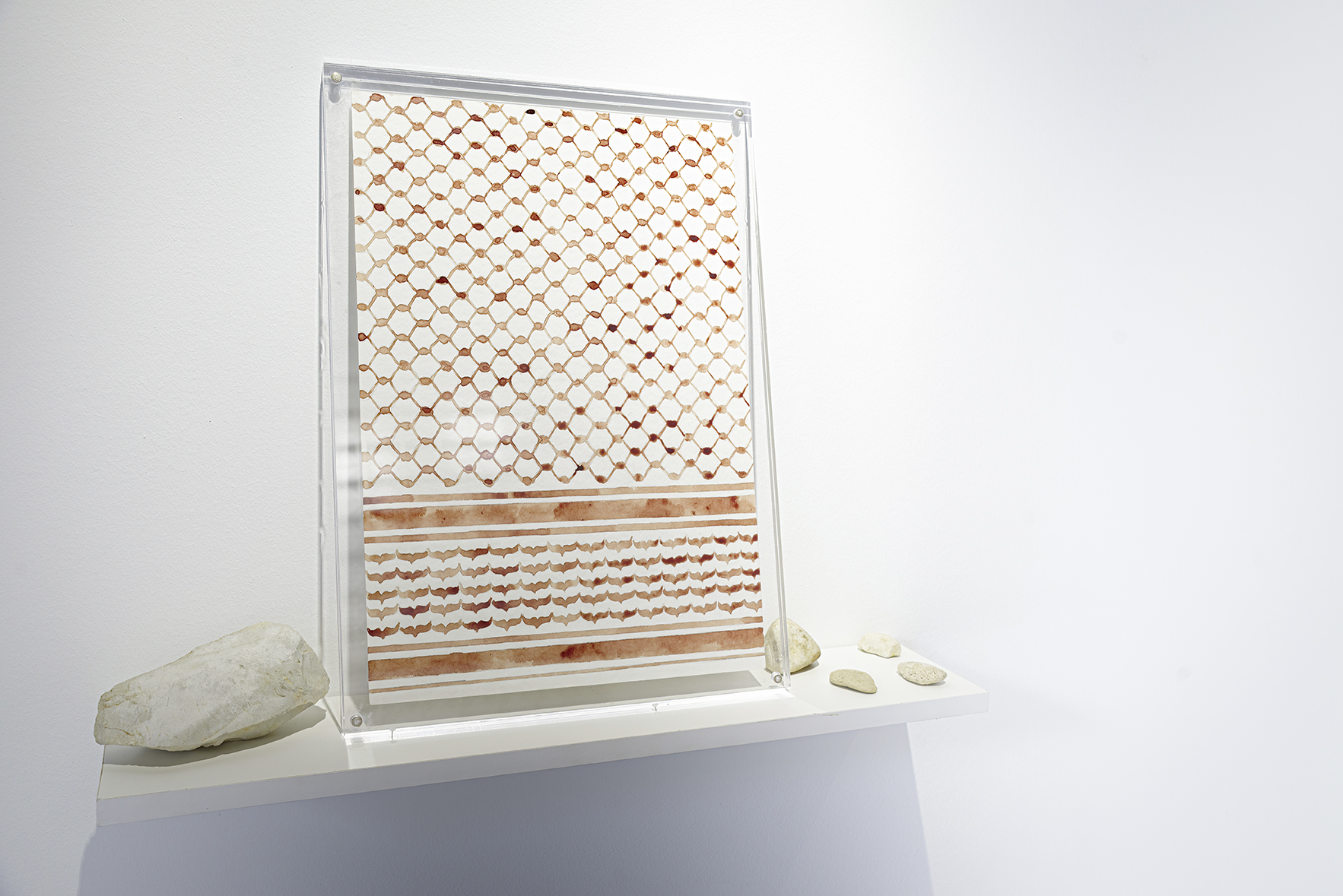 Installation view of water-color drawing with autologuous blood and stones sealed between two acrylic sheets.
