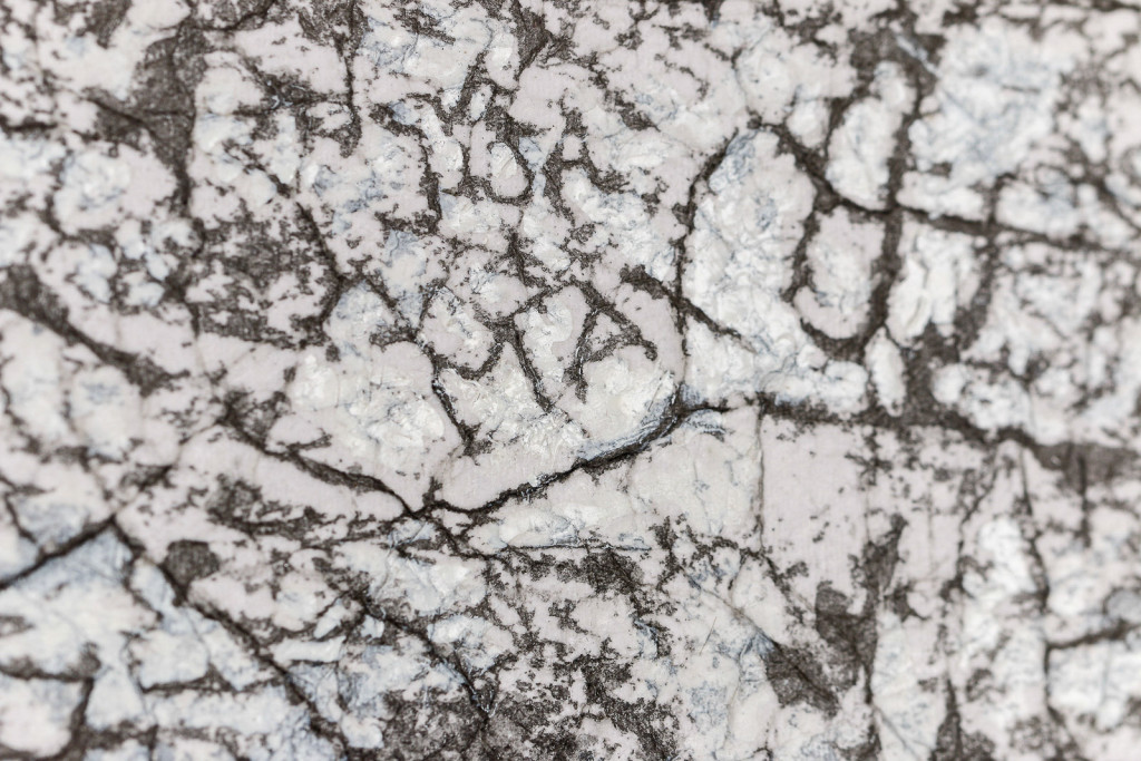 Detail of a canvas surface with a frottage pattern, taken from a wall with cracks and engraved names.