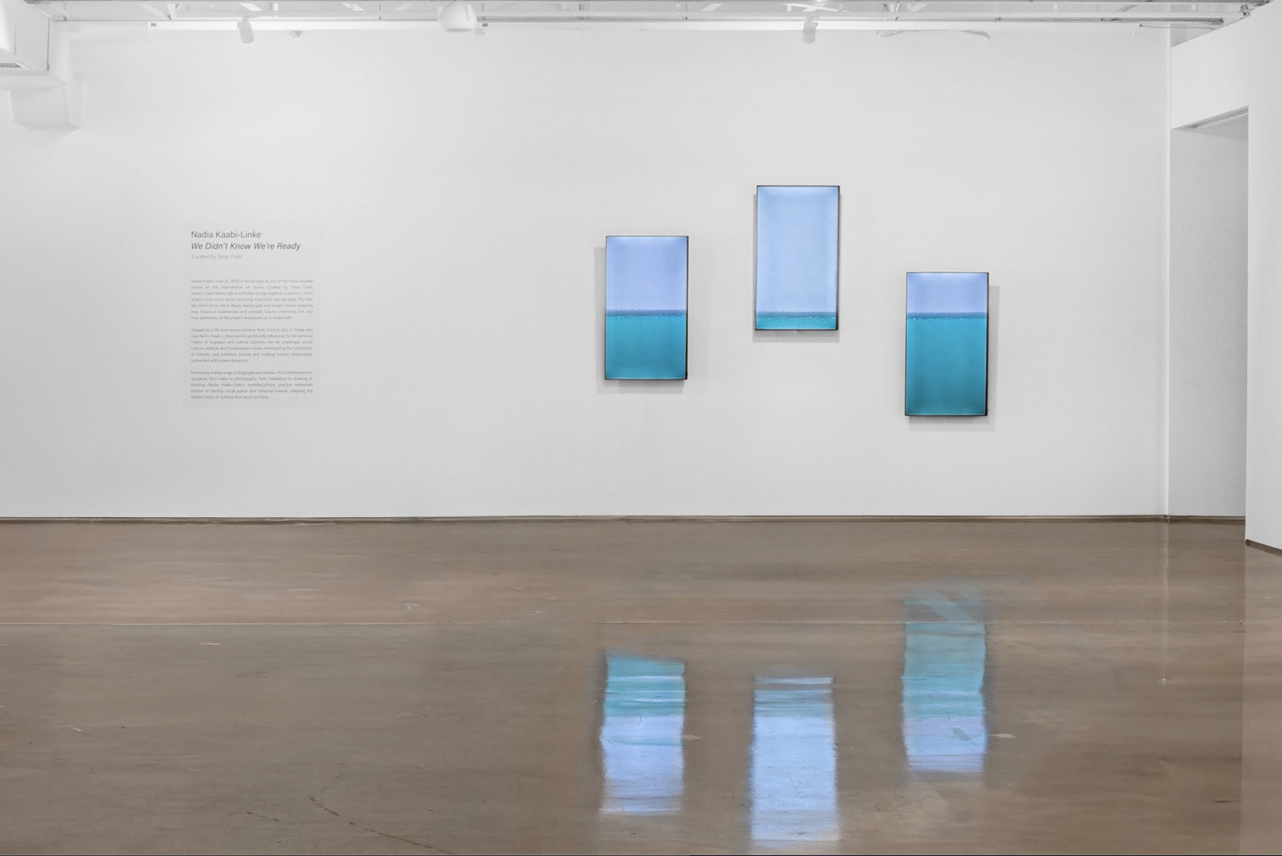 A video of the sea divided on three vertical screens hanging on an exhibition wall. Nadia Kaabi-Linke Under Sea Heart Beats