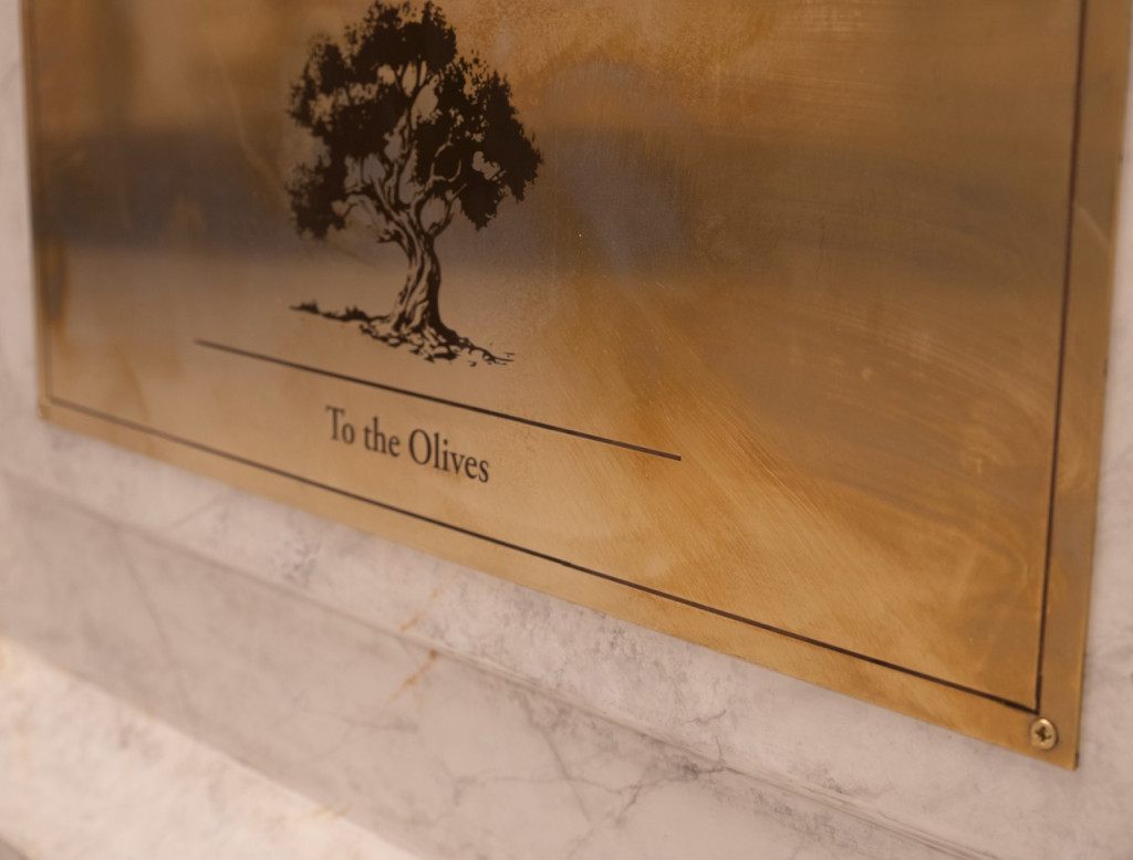 Nadia Kaabi-Linke, To the Olives, 2026. Detail of the brass label engraved with an olive tree and the title To the Olives, mounted on the marble plinth.