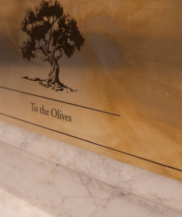 Nadia Kaabi-Linke, To the Olives, 2026. Detail of the brass label engraved with an olive tree and the title To the Olives, mounted on the marble plinth.